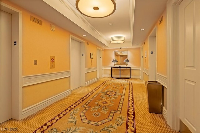 hall with crown molding, elevator, light colored carpet, and a tray ceiling