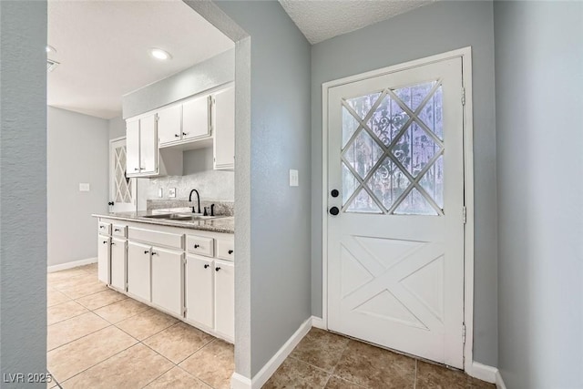 doorway to outside featuring sink, a textured ceiling, and light tile patterned flooring