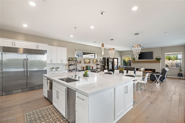 kitchen with hanging light fixtures, appliances with stainless steel finishes, sink, and white cabinets