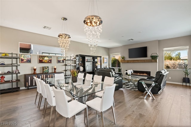 dining area with hardwood / wood-style flooring, plenty of natural light, and a chandelier