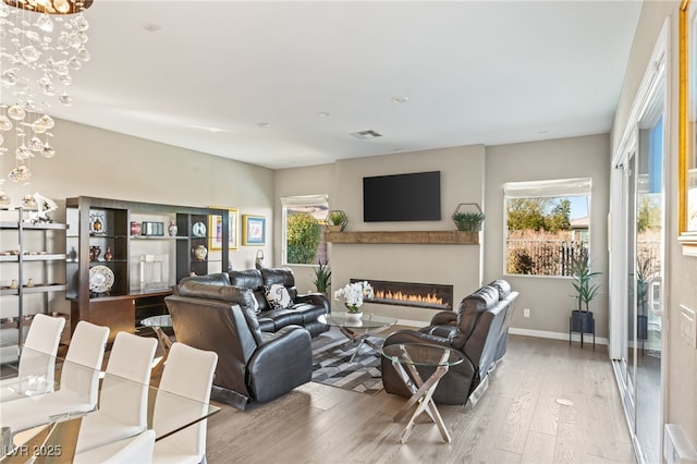 living room featuring plenty of natural light, light hardwood / wood-style floors, and a notable chandelier