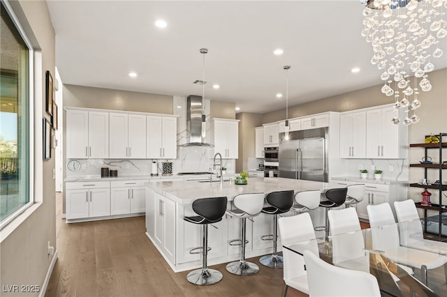 kitchen with white cabinetry, wall chimney exhaust hood, and stainless steel built in fridge