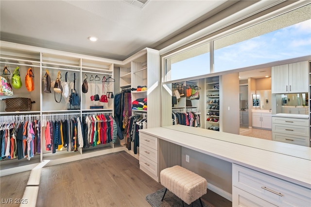 spacious closet featuring built in desk and light hardwood / wood-style floors