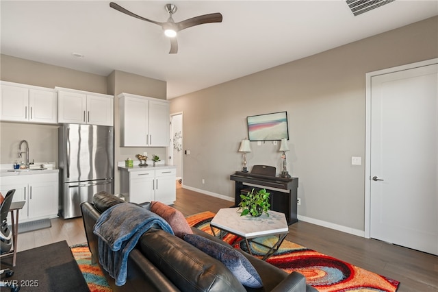 living room with dark hardwood / wood-style flooring, sink, and ceiling fan