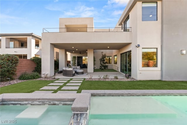 rear view of house featuring an outdoor living space, a lawn, a patio, and a balcony