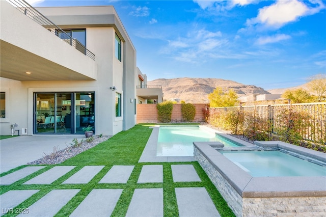 view of swimming pool featuring a mountain view, a patio area, and an in ground hot tub