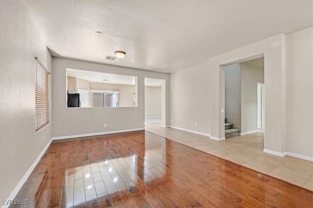 unfurnished living room featuring light hardwood / wood-style flooring and a textured ceiling