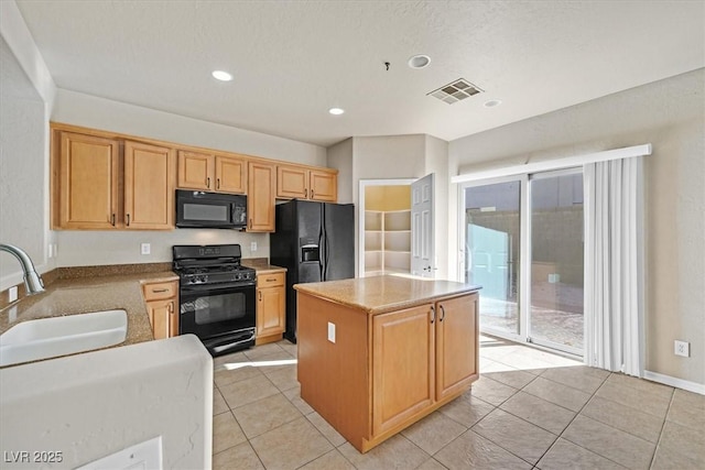 kitchen featuring sink, light tile patterned floors, black appliances, and a center island