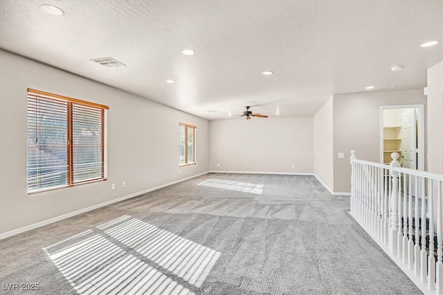 carpeted empty room with ceiling fan and a textured ceiling