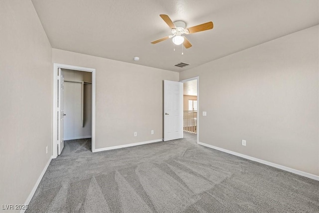 unfurnished bedroom featuring a walk in closet, carpet flooring, ceiling fan, and a closet