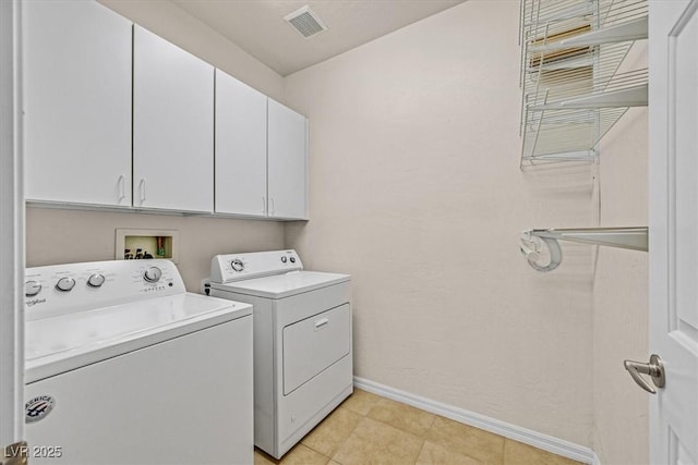 clothes washing area featuring cabinets, washing machine and dryer, and light tile patterned floors