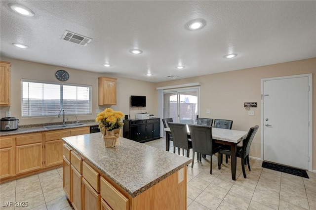 kitchen featuring a center island, sink, a textured ceiling, and light brown cabinets