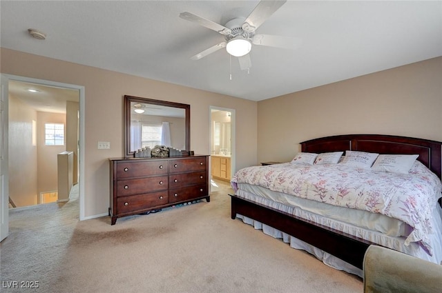 bedroom featuring light colored carpet, ceiling fan, and ensuite bath