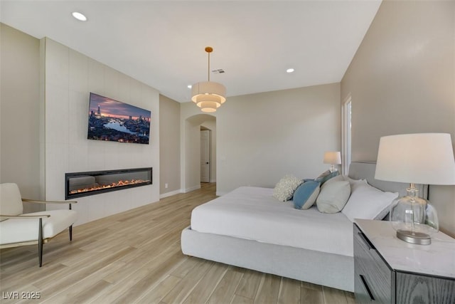 bedroom featuring a fireplace and light wood-type flooring