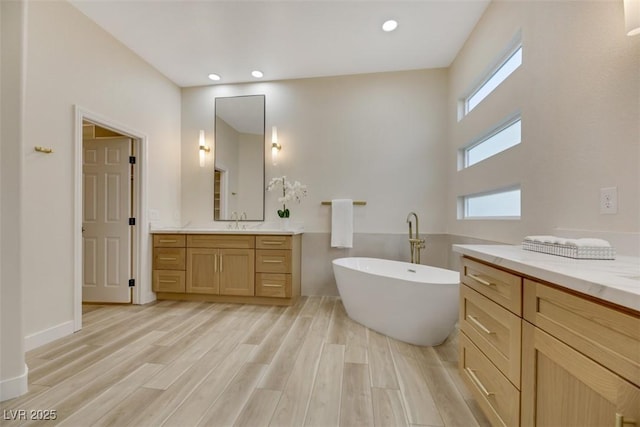 bathroom with hardwood / wood-style flooring, vanity, and a tub to relax in