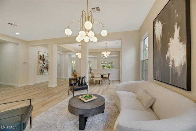 living room featuring a wealth of natural light, an inviting chandelier, and light hardwood / wood-style floors