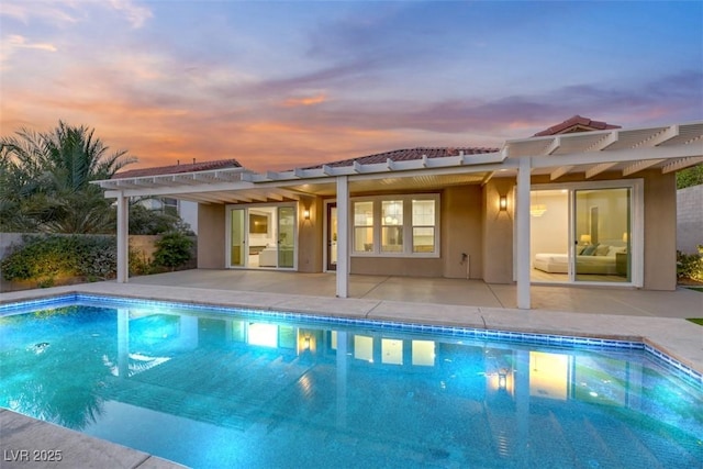 pool at dusk featuring a pergola and a patio area