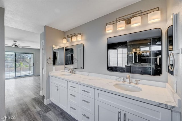 full bath with a ceiling fan, double vanity, a sink, and wood finished floors