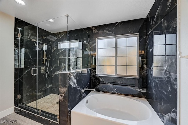 bathroom with a garden tub, tile walls, and a marble finish shower