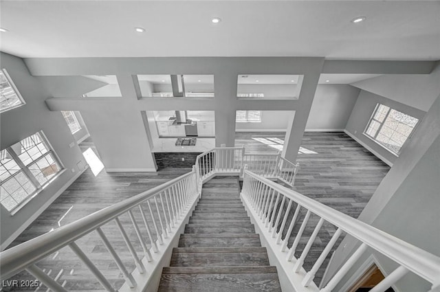 stairs with baseboards, wood finished floors, and recessed lighting