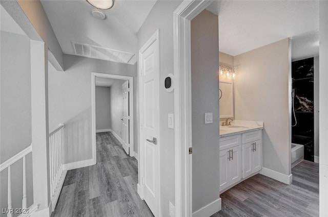 hallway featuring light wood-type flooring, baseboards, and a sink