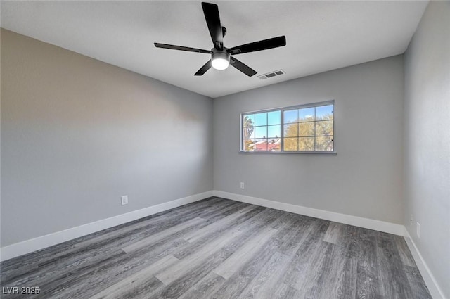 spare room featuring visible vents, ceiling fan, baseboards, and wood finished floors