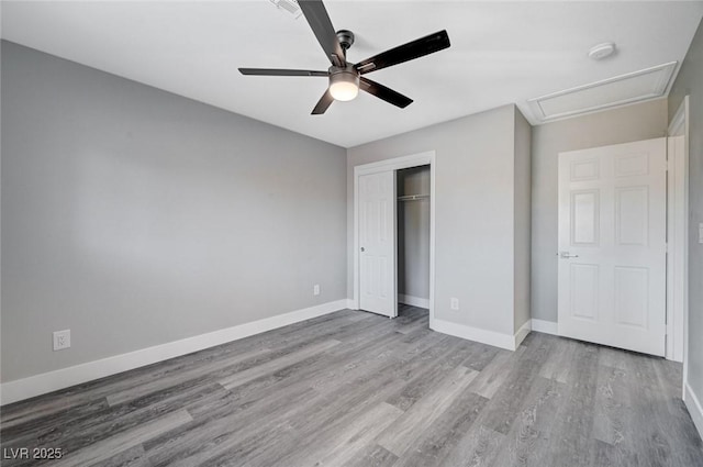 unfurnished bedroom featuring ceiling fan, baseboards, a closet, and wood finished floors