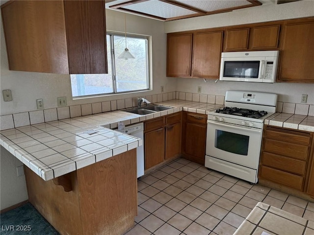 kitchen with sink, white appliances, tile countertops, and kitchen peninsula