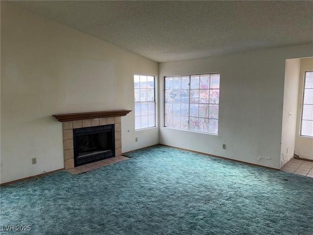 unfurnished living room with light colored carpet, lofted ceiling, a fireplace, and a textured ceiling