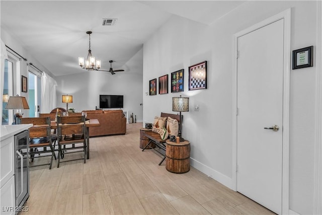 dining area featuring a notable chandelier, beverage cooler, and light hardwood / wood-style flooring