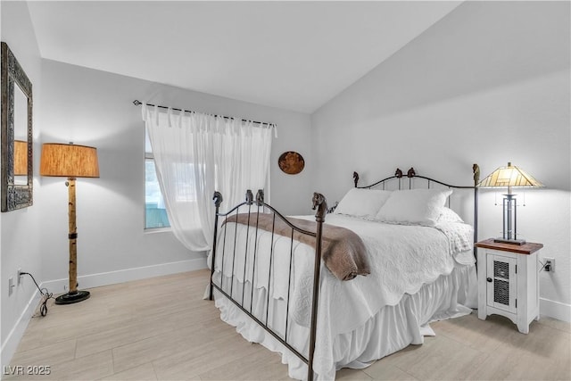 bedroom with vaulted ceiling and light wood-type flooring