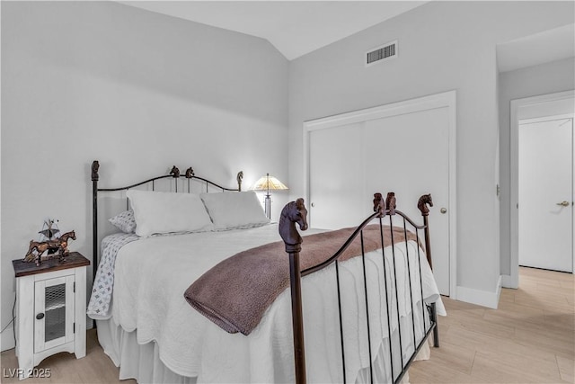 bedroom featuring vaulted ceiling, light hardwood / wood-style floors, and a closet