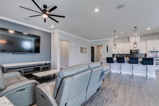 living room featuring crown molding, ceiling fan, and light wood-type flooring