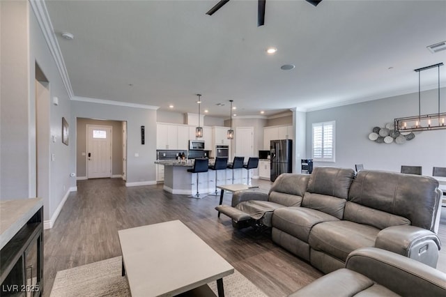 living room with dark hardwood / wood-style flooring, a notable chandelier, and crown molding