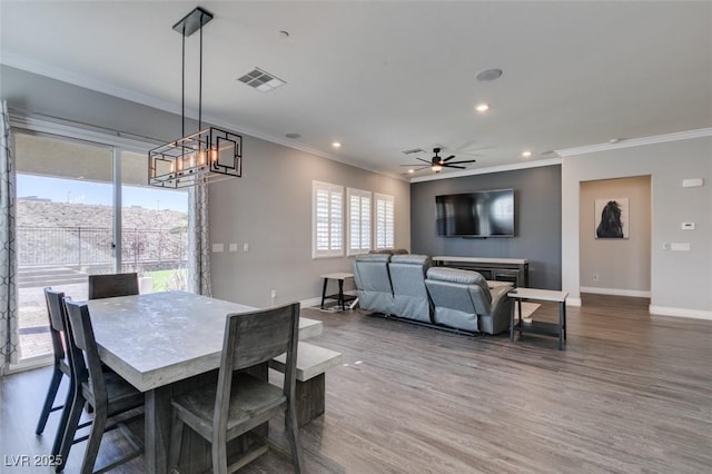 dining room featuring crown molding, wood-type flooring, and ceiling fan with notable chandelier