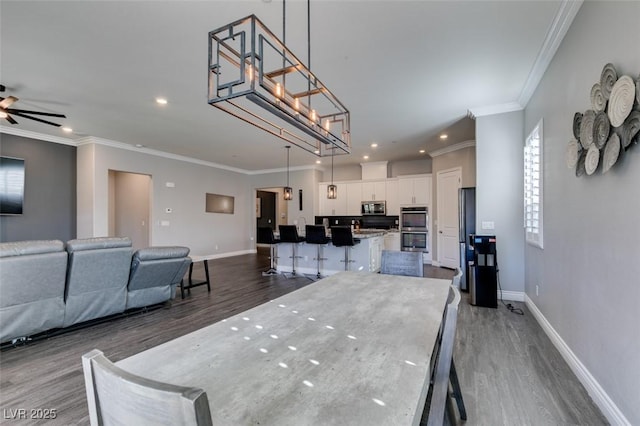 dining area with crown molding, ceiling fan, and wood-type flooring