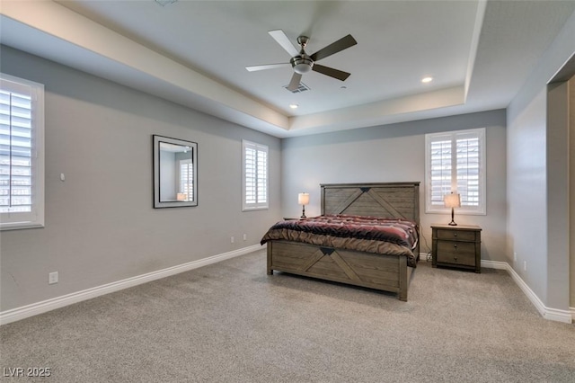 bedroom with light carpet, ceiling fan, and a tray ceiling