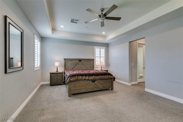 carpeted bedroom featuring a raised ceiling and ceiling fan