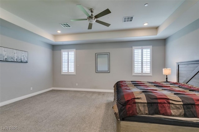 carpeted bedroom featuring ceiling fan and a raised ceiling