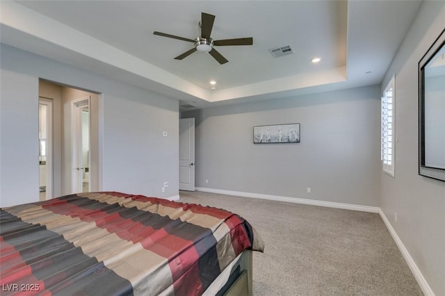 carpeted bedroom featuring a raised ceiling and ceiling fan