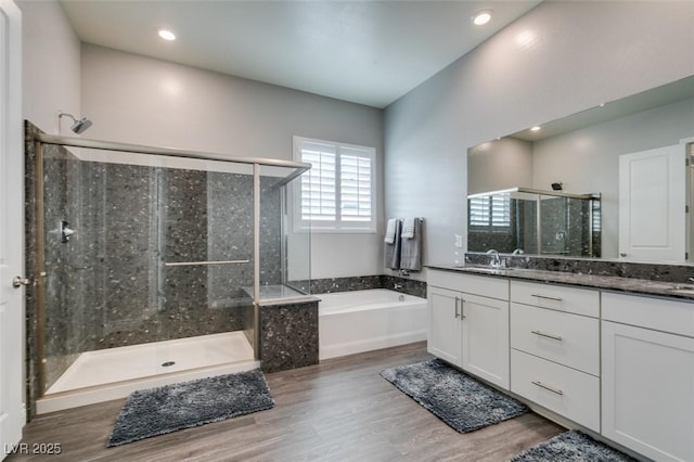 bathroom featuring plus walk in shower, hardwood / wood-style floors, and vanity