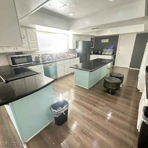 kitchen with a kitchen island, a breakfast bar, white cabinets, and appliances with stainless steel finishes