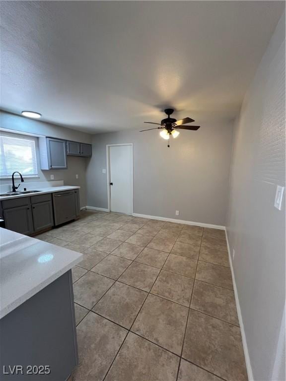 kitchen featuring sink, gray cabinetry, light tile patterned floors, stainless steel dishwasher, and ceiling fan