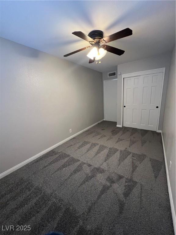 unfurnished bedroom featuring ceiling fan, dark carpet, and a closet