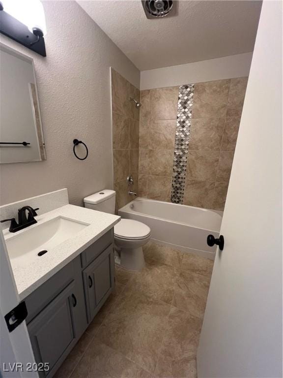 full bathroom featuring tiled shower / bath combo, vanity, a textured ceiling, and toilet