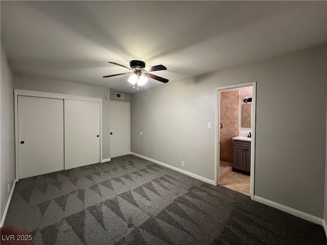 unfurnished bedroom featuring a closet, light carpet, ceiling fan, and ensuite bath