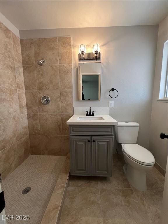 bathroom with vanity, a tile shower, tile patterned floors, and toilet