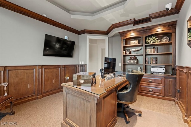 carpeted office with ornamental molding and a tray ceiling