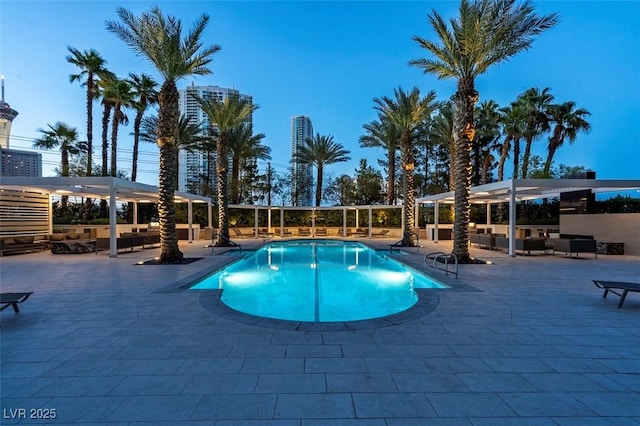 pool at dusk featuring a patio area