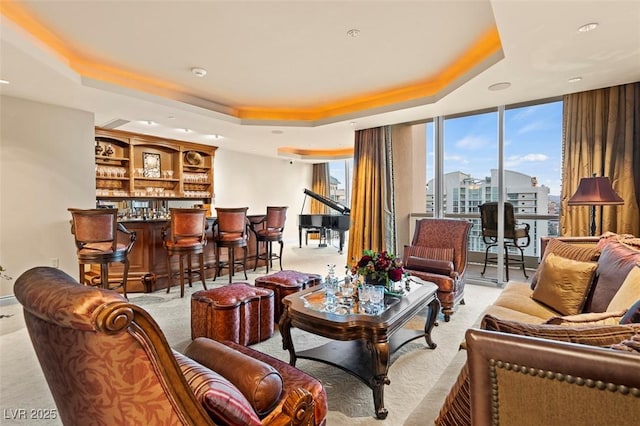 living room featuring bar, a wall of windows, and a tray ceiling